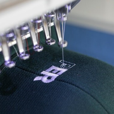 Closeup of custom hat being embroidered on a 6 color embroidery Machine